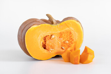 Half of a ripe orange pumpkin next to diced pumpkin pulp on a white background. Seasonal autumn dietary vegetables for a vegan or vegetarian diet. Ingredients for a healthy diet.