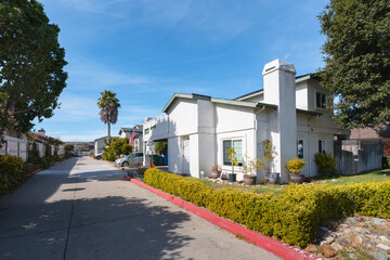 A street view photo of a row of modern condominiums nestled beneath the warm California sun