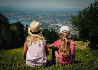 dziewczynki siedzące na wzgórzu patrzące w dal