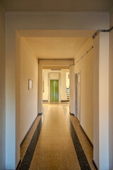 Interior hallway of 1960s Italian apartment building with marble and quartz mosaic grit tile floor and elevator door at the bottom