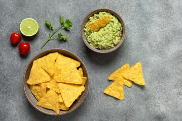 Guacamole with nachos on a gray background. Mexican food. Top view, flat lay, copy space.