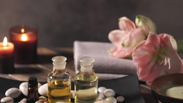 Beauty spa treatment with oils, laminaria algae in bowl and candles on dark background
