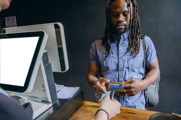 Black male customer of African ethnicity handing his debit card to waiter to pay for food order