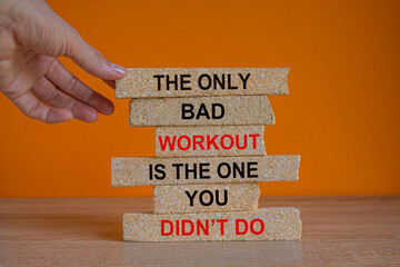 The only bad workout is the one you didn't do. Red words on brick blocks. Beautiful wooden table orange background. Businessman hand