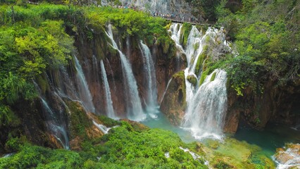 Obraz premium Tourists visit famous Plitvice waterfalls in Croatia. Mountain streams flow into a lake with azure clear water. Summer National Park.