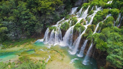 Obraz premium Beautiful waterfalls in summer National Park. Scenic mountain streams flow into a lake with aquamarine clear water. Summer landscape.