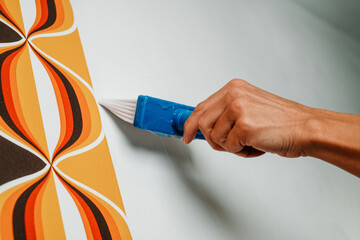 man applies some glue with a brush to the wall - Powered by Adobe