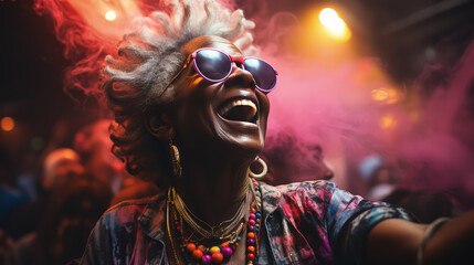 Stylish elderly African American woman in fashionable glasses dances funny in a nightclub. Senior woman having fun in neon lighting.