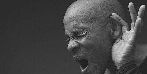 deaf man suffering from deafness and hearing loss on grey black background with people stock image...