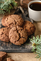 Homemade christmas chocolate cookies on wooden board and coffee on brown festive background with fir tree branches. Christmas holiday desserts