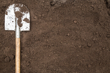 Brown soil ground texture background with copyspace and shovel on garden bed in farm garden. Organic farming, gardening, growing, agriculture concept - obrazy, fototapety, plakaty