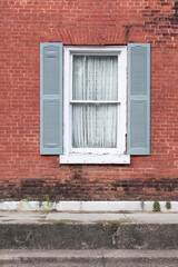 Old window and blue shutters in brick wall