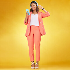 Happy woman, headphones and phone for music in studio for fashion, podcast and app on yellow background. Indian model, style and listening to audio technology, streaming mobile sound and online radio