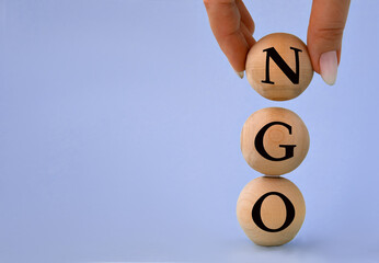 A woman's hand holds a wooden ball with the abbreviation NGO