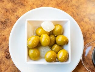 Green olives with pits in bowl with pickled onions