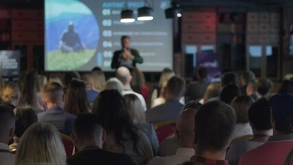 Back view of diverse business professionals attending presentation in projection room at export forum