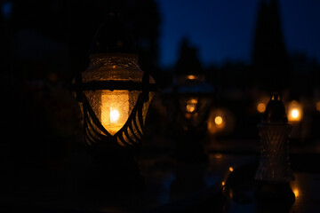 Candle light in the cemetery at night. Selective focus.All saint's day.  Lanterns in the cemetery at night.Lantern on the background of burning candles in the night.