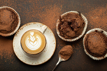 Chocolate and cocoa browny muffins with coffee cappuccino in cup top view on brown rustic stone...