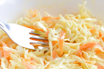 Coleslaw salad with carrot and cabbage on a white bowl.