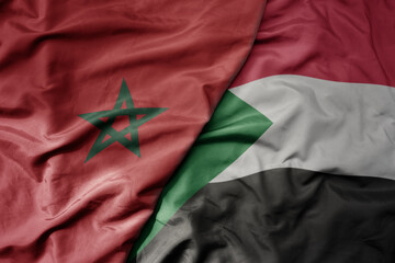 big waving national colorful flag of morocco and national flag of sudan .