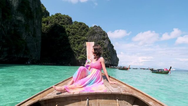 Happy Asian woman traveler sitting enjoy relaxing on long tail boat, Phi Phi island, Andaman sea, Phuket, Travel Thailand Asia, Beautiful landscape nature. Summer holiday outdoor vacation trip.