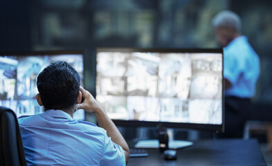 Security guard in control room, man checking cctv screen in surveillance office for building...