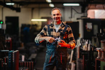Fototapeta na wymiar A portrait of a metal work expert holding a caliper and a metal part.