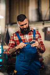 A tattooed metal turner measuring a metal ring with a caliper, tattooed.