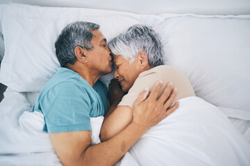 Top view, hug and senior couple in bed, love and sleeping with retirement, wake up or happiness with a kiss. Romance, old man or elderly woman embrace, bedroom or holiday with marriage or loving - obrazy, fototapety, plakaty