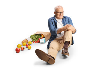 Mature man with a bicycle with a grocery bag holding injured from a fall on the ground