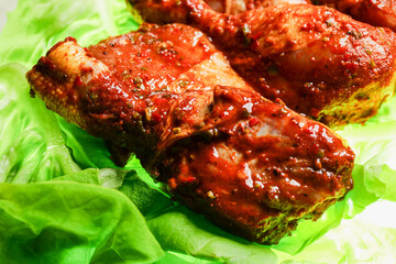 Spicy uncooked marinated chicken drumsticks on a green fresh lettuce leaf. Summer time barbeque concept. Tasty poultry product for cooking on fire or grill.