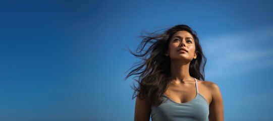 Young Hispanic woman looking at sunny blue sky