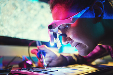 Woman, motherboard and engineering with soldering iron for manufacturing, microchip and night....