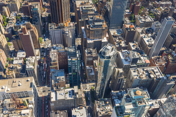 Aerial view from Empire State Building of rooftops of skyscrapers and bustling 34th Street in Manhattan, with transportation visible below. New York, USA.
