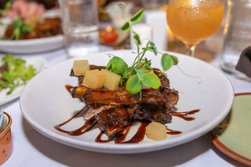 Hawaiian style sticky sweet barbeque ribs with chunks of pineapple and a pea sprout garnish. 
