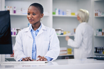 Pharmacist, typing and black woman on computer in pharmacy, drugstore or shop. Wellness, medical...