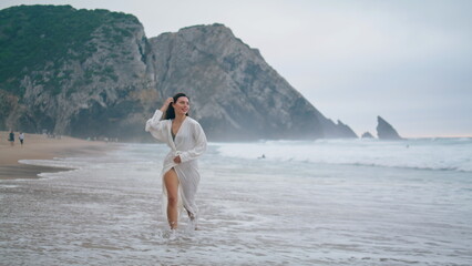 Serene girl running ocean beach on cloudy evening. Woman jogging on sea waves.