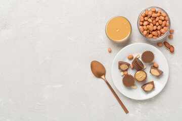 Delicious peanut butter cups with nuts on concrete background, top view