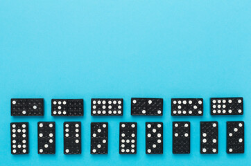 Black domino tiles on color background, top view