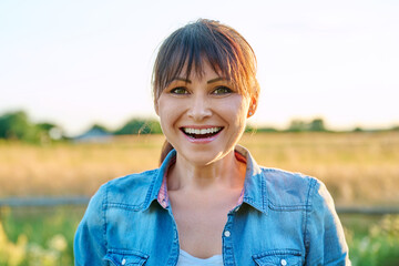 Portrait of smiling middle aged woman looking at camera, summer countryside