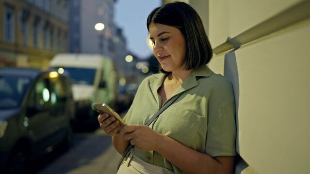 Young beautiful hispanic woman smiling happy using smartphone in the streets at night