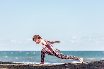 Young caucasian woman practicing yoga at seashore - 671874498