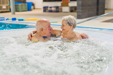 Fototapeta premium cute Caucasian senior couple enjoying the hot bubbly bath in the pool, old people concept. High quality photo