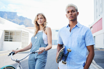 Bike, skate and portrait of urban couple, gen z street fashion and outdoor activity. Young city man and woman, streetwear and alternative transport, carbon neutral travel with skateboard and bicycle.