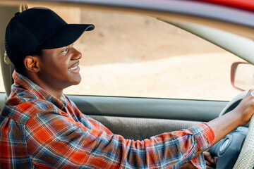 young handsome African car driver smiling holding car steering
