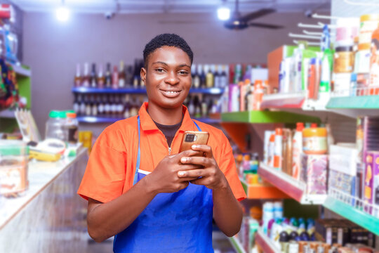 handsome young African supermarket sales attendant holding cell phone