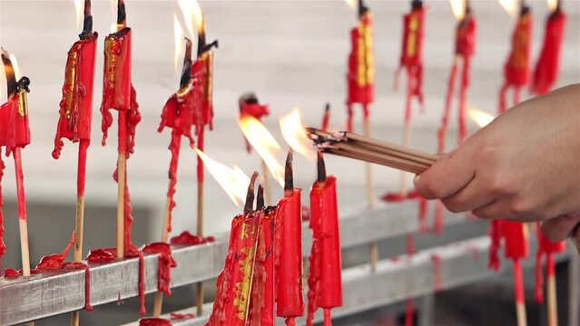 Lighting incense sticks using burning candles in the Buddhist temple