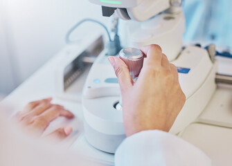 Ophthalmology, test and hand of a doctor on a machine for a consultation, vision check and monitor lens. Medicine, healthcare and optician moving a handle on equipment for analysis of eyes and retina