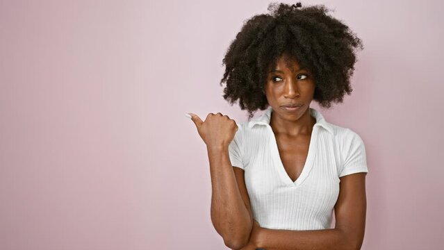 African american woman pointing to the side saying no with finger over isolated pink background