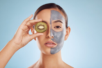 Portrait, kiwi and mask for beauty with a woman in studio on a blue background for antiaging skincare. Face, facial and fruit with an attractive young female holding a berry for natural treatment